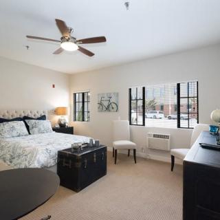 A modern bedroom with a comfortable bed, stylish decor, and large windows.
