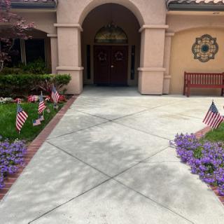 A welcoming entrance featuring a decorated pathway with floral arrangements and American flags.