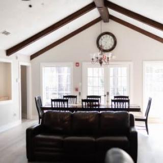 A stylish living and dining area with a vaulted ceiling and wooden beams, featuring a cozy leather sofa.