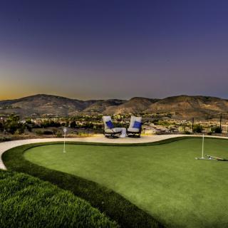 A scenic sunset view over a golf course with outdoor seating overlooking rolling hills.