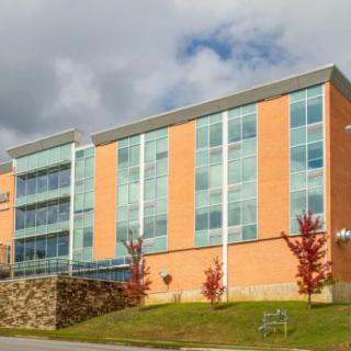 A modern building with a brick and glass facade under a partly cloudy sky.