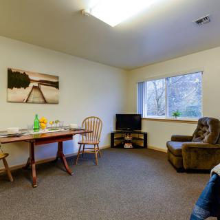A cozy living room with a dining table, chairs, and a TV near the window.