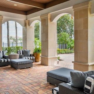 A stylish outdoor patio featuring comfortable seating and elegant columns, with a view of the garden.