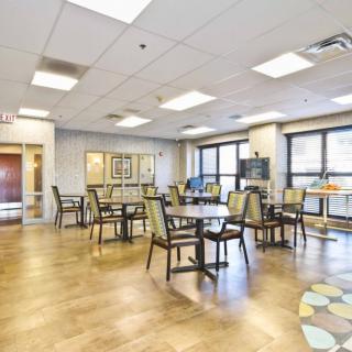 A bright and spacious dining area with multiple tables and chairs, featuring large windows that allow natural light to fill the room.