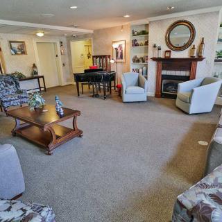 A cozy living room featuring a fireplace, comfortable seating and a piano.