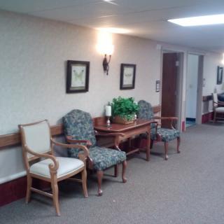 A hallway with seating and decor, featuring chairs and framed pictures.