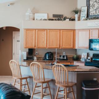 A warm and inviting kitchen featuring wooden cabinets, bar stools, and modern appliances.