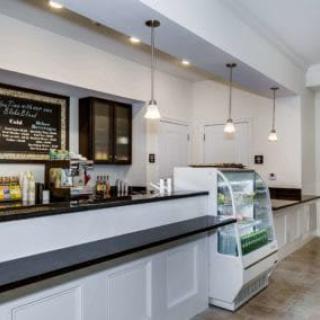 A modern cafe interior with a counter, menu board, and display case.