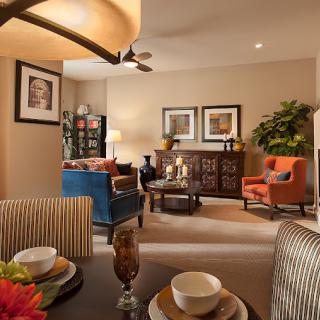 A warmly lit living room featuring modern decor, with colorful furniture and framed artwork.