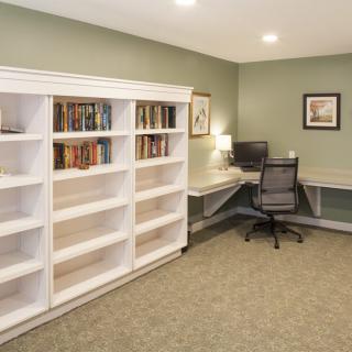 A cozy home office with a desk, computer, and a large white bookshelf in the corner.