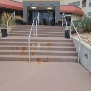 A set of stairs leading to a building entrance, showing visible rust stains on the steps.