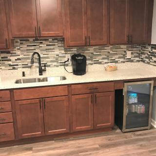 A modern kitchen featuring wooden cabinets, a stone backsplash, and a sleek countertop with a sink and small appliances.