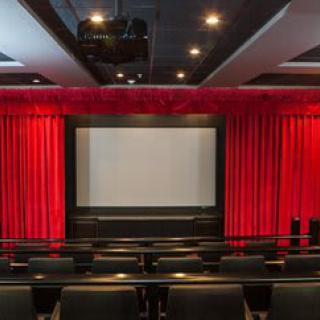 An empty cinema hall with red curtains and a large movie screen.