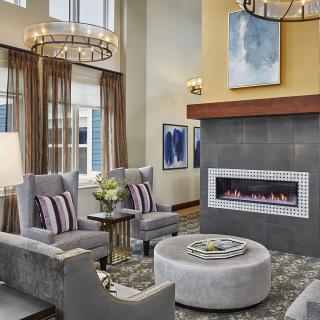 A modern living room featuring a sleek fireplace, elegant chandeliers, and contemporary seating arrangements.