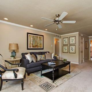 A well-decorated living room featuring a comfortable sofa, coffee table, and stylish artwork with a ceiling fan overhead.