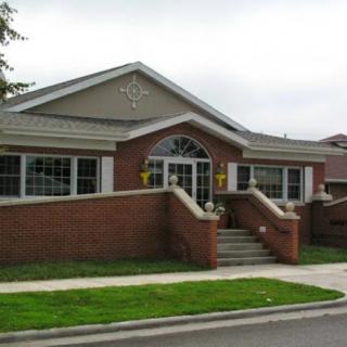 A brick building with large windows and steps leading to the entrance.