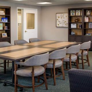 An organized conference room with a large meeting table and bookshelves.