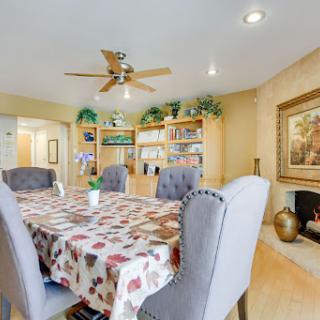 A cozy and well-decorated dining room featuring a large table, comfortable chairs, and shelves filled with books.