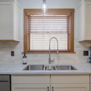 A modern kitchen with a dual sink and a window with wooden blinds.
