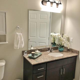 A neatly organized bathroom with a stylish vanity and mirror, decorated with flowers and towels.
