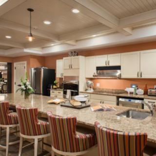 A modern kitchen with an island, equipped with bar stools and stylish lighting.