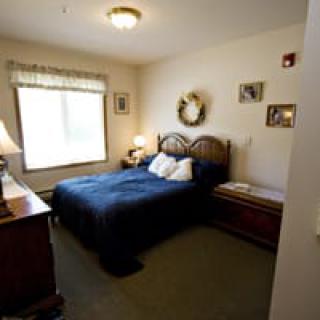 A cozy bedroom with a neatly made bed, featuring warm lighting and decorative elements.