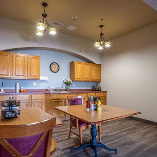 A cozy kitchen and dining area with wooden cabinets, tables, and chairs.