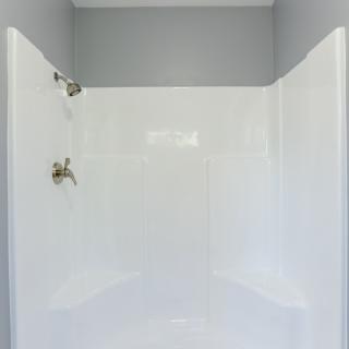 A clean and minimalist bathroom shower with white walls.