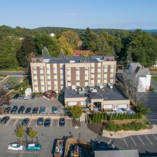 Aerial view of a hotel with a parking lot and surrounding greenery.
