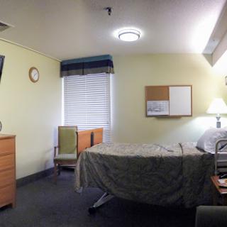 A panoramic view of a hospital room featuring a bed, furniture, and essential amenities.