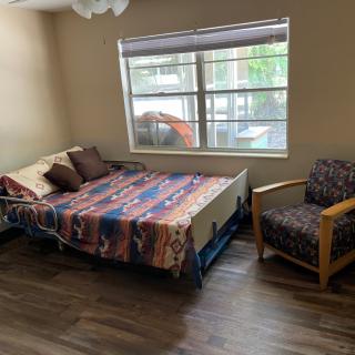 A cozy bedroom with a colorful bedspread, chair, and large window.