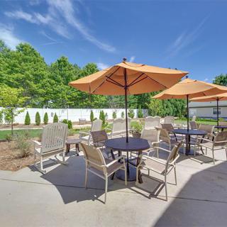 A sunny outdoor patio area with tables, chairs, and umbrellas set up for relaxation.