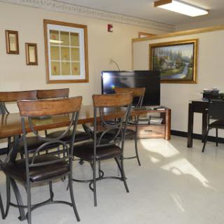 A cozy dining area featuring wooden furniture, a television, and artwork on the walls.