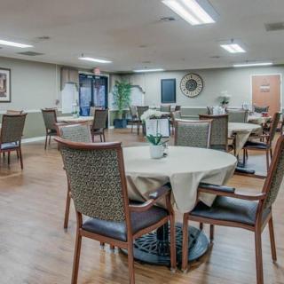 A well-lit dining room with several round tables and chairs, featuring simple decor.