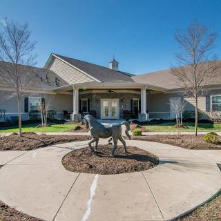 A beautifully landscaped courtyard with a horse statue in front of a large building.