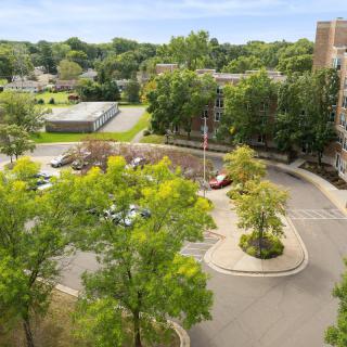A view overlooking a parking area surrounded by trees and buildings.