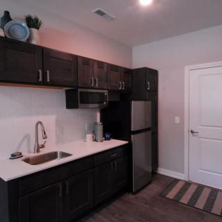 A modern kitchen with dark cabinets and stainless steel appliances.