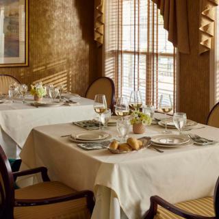 An elegant dining room with tables set for a meal, complete with glasses, silverware, and decorative elements.