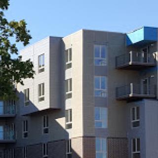 A modern residential building featuring balconies and large windows.