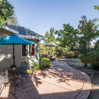 A sunny backyard patio with outdoor furniture and a garden setting.