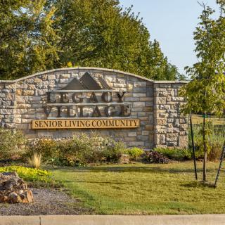 Entrance sign for a senior living community surrounded by greenery.