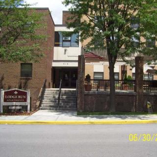 A brick building with an entrance and stairs, surrounded by trees.