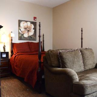A cozy bedroom with a four-poster bed, sofa, and soft lighting.