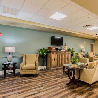 A cozy lounge area with comfortable seating, tables, and a television on the wall.
