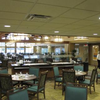 A spacious indoor dining area with tables and chairs, featuring a buffet section.