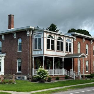 An elegant brick house featuring large windows and a welcoming front porch.