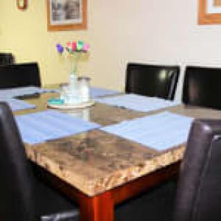 A dining table set with blue placemats and a vase of flowers in a cozy dining area.