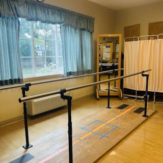 A physical therapy room featuring parallel bars for rehabilitation exercises.
