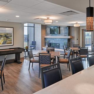 A modern lounge area featuring comfortable seating, a fireplace, and large windows.