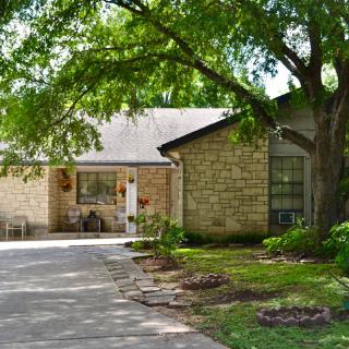 A cozy residential house with a brick exterior and a shaded driveway.